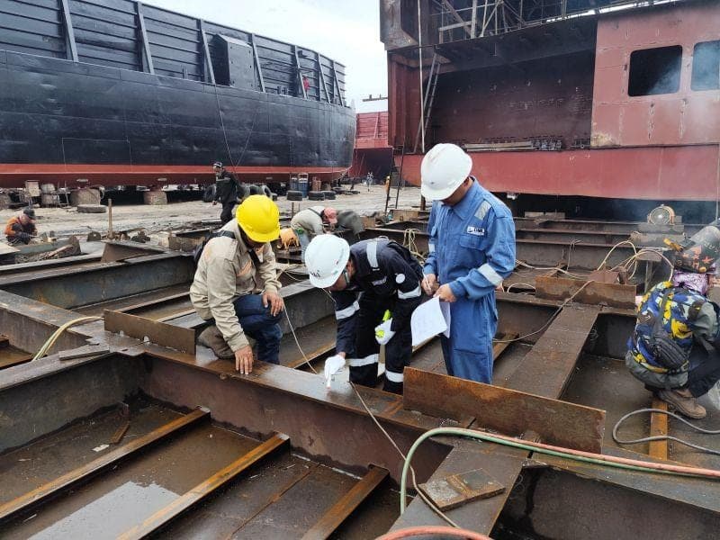 Inspection team checking steel sections in a shipyard