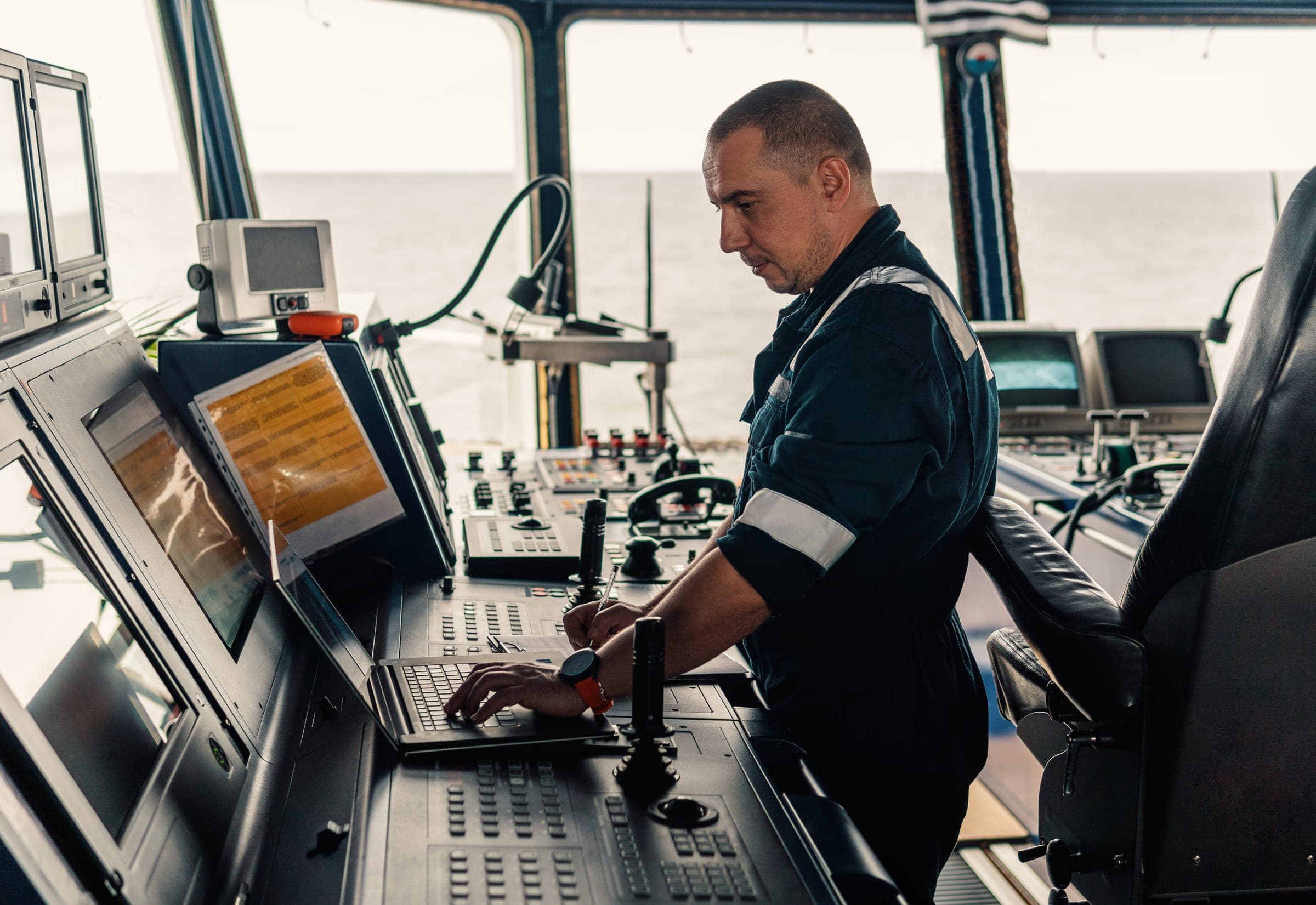 Officer working at a laptop on the ship bridge