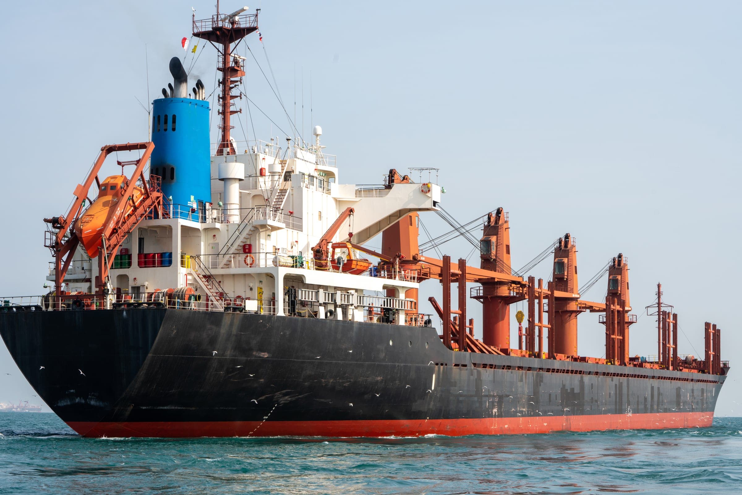 Bulk carrier with deck cranes lying off the coast