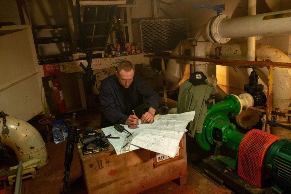 Engineer reviewing drawings at a desk in the machinery space
