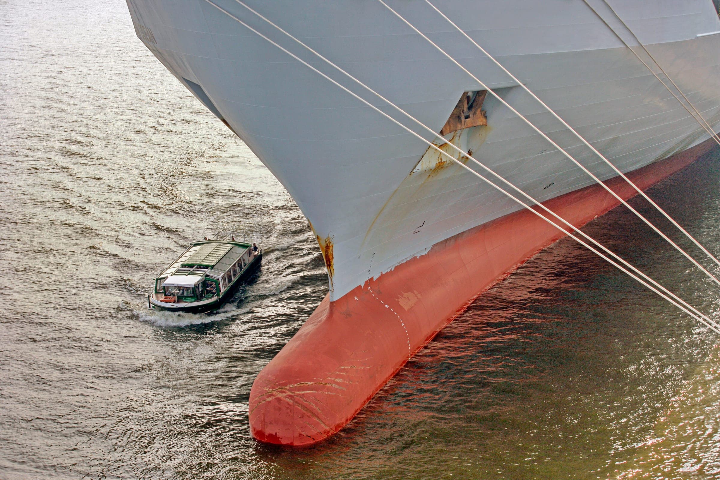 Pilot boat running alongside the bow of a large vessel